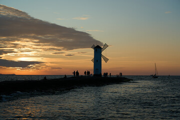 old fashioned windmill on the rocky pier at the coastline of usedom island along the baltic sea of...
