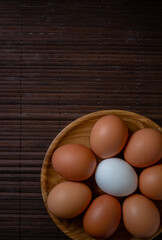 Fresh chicken eggs in wooden plate on the table, selective focus