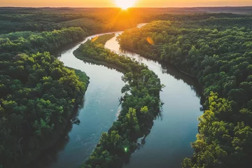 The sun sets over a serene river winding through a forested landscape © Creative_Bringer