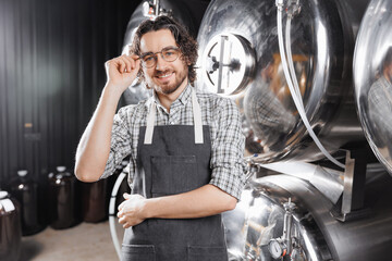Portrait smile bearded man brewer in apron on background beer tank. Concept owner small business of...