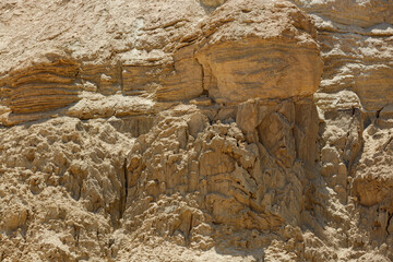 Detailed view of a rocky terrain. Upper section displays smooth, layered rocks indicating erosion over time. Below jagged and rough textures dominate suggesting a more tumultuous environmental impact