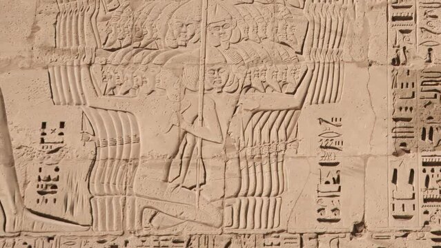 Ancient Egyptian hieroglyphs and bas-reliefs close-up in Temple of Medinet Habu. Egypt, Luxor. The Mortuary Temple of Ramesses III at Medinet Habu located in the West Bank of Luxor in Egypt.