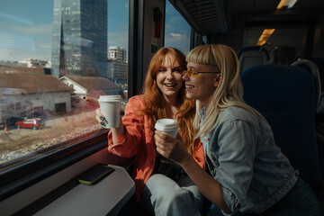 Smiling friends with coffee cups on train