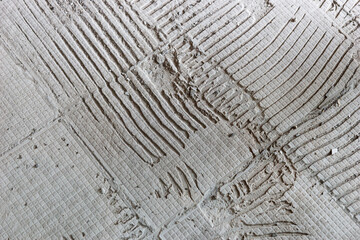 Background of old tile adhesive on the floor. Abstract pattern of notched trowel