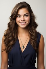 Fototapeta premium Beautiful young woman with long brown hair smiling wearing a blue dress
