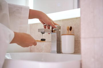 Women's hands under running water in the bathroom. Morning routine.