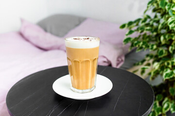 Hot creamy coffee with milk with cinnamonin in the bedroom. Hot latte coffee drink in glass with...