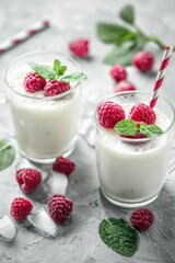 Fresh milk in glasses with raspberries and mint leaves, perfect for food and drink concepts