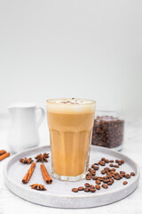 Coffee latte in glass with cinnamon, spices and roasted coffee beans. Creamy coffee with milk. Coffee drink recipe. 