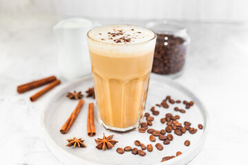 Coffee latte in glass with cinnamon, spices and roasted coffee beans. Creamy coffee with milk....