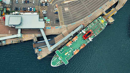 Aerial View of Cargo Ship Docked at Industrial Port. Top-down aerial shot capturing a large cargo...