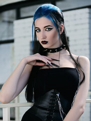 Close-up indoor portrait of beautiful goth (informal) girl dressed in black dress and corset. Dark...