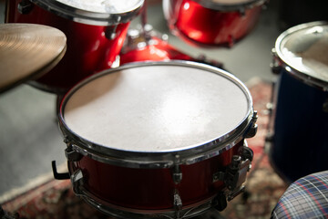 Fototapeta na wymiar Close-Up View of a Red Acoustic Drum Set With Cymbals and Stool in a Music Studio