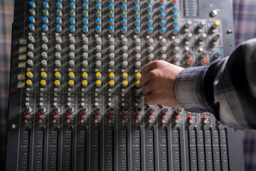 Close-Up of a Hand Adjusting the Controls on a Music Mixer Console in a Studio - 766503785