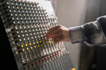 Close-Up of a Hand Adjusting the Controls on a Music Mixer Console in a Studio - 766503792