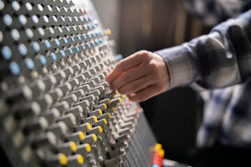 Close-Up of a Hand Adjusting the Controls on a Music Mixer Console in a Studio - 766503796