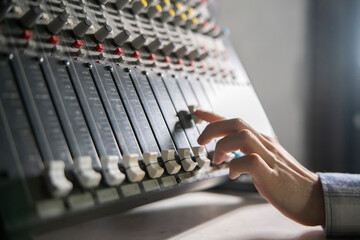 Sound Engineer Adjusting Faders on a Mixing Console During Studio Session - 766503939