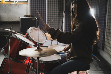 Smiling Woman Playing Drums Enthusiastically in a Music Studio Setting