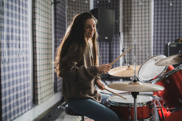 Smiling Woman Playing Drums Enthusiastically in a Music Studio Setting - 766505505