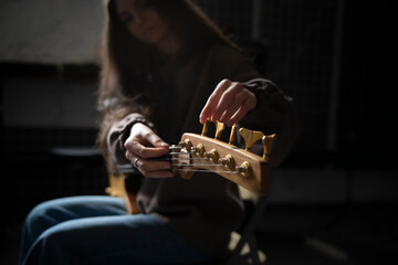 Musician Fine-Tuning Acoustic Guitar Strings in a Dimly Lit Room of music studio