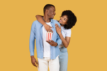 Affectionate and joyful couple sharing a moment of laughter and closeness with a box of popcorn