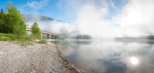 fog over lake Sylvensteinsee, gravel beach and bridge, spring landscape upper bavaria