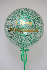 transparent bubbles balloon with green confetti and the inscription 