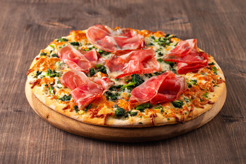 Pizza with prosciutto, ham, arugula, tomatoes, pesto, cheese and parmesan. Italian cuisine. 