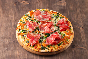Pizza with prosciutto, ham, arugula, tomatoes, pesto, cheese and parmesan. Italian cuisine. 