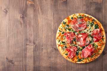 Pizza with prosciutto, ham, arugula, tomatoes, pesto, cheese and parmesan. Italian cuisine. 