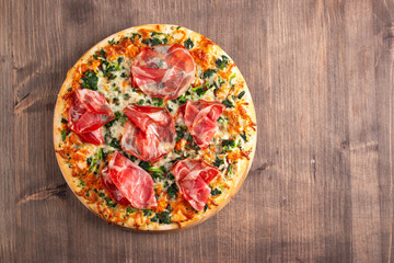 Pizza with prosciutto, ham, arugula, tomatoes, pesto, cheese and parmesan. Italian cuisine. 