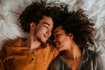 Multiracial couple lying on a white bed in a top-down shot