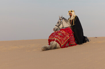 Saudi Man with his white stallion in a desert