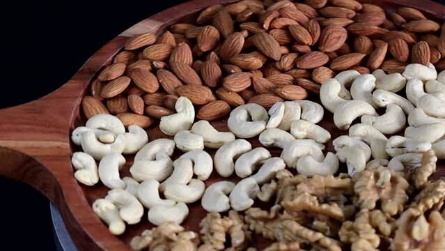 Almonds, Cashews, and Walnuts on display. Exquisite arrangement of almonds, cashews, and walnuts on a rustic wooden tray