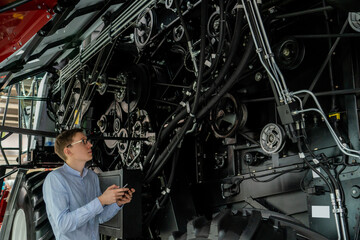 Serviceman with digital tablet next to combine harvester with open hood