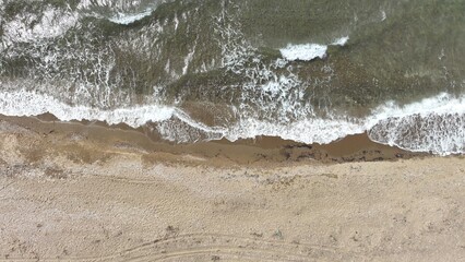 Bird's eye view of the Aegean Sea, blue waves hitting the shore and breaking on the sand. Beautiful...