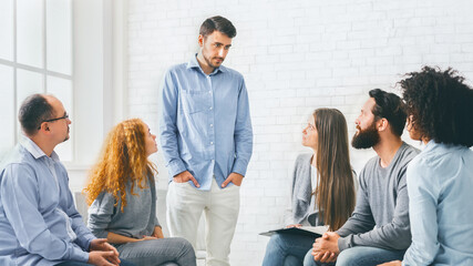 Young man talking about his problems during group therapy