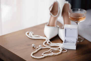 Closeup Bridal accessories with wedding rings. Elegant shoes, perfume, pearl macro photo