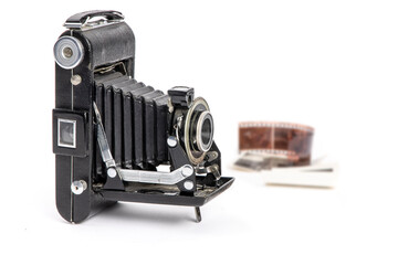 An antique old bellows camera with old film strip and photos in the background isolated on white