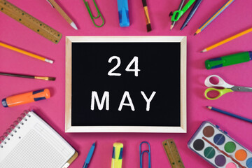 May 24 written in chalk on black board. Calendar date 24th of May on chalkboard on pink blurred school stationery background. Event schedule date. School, study, education concept. Month of spring.