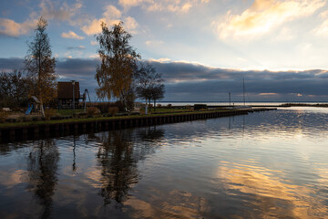 Sunset at the Achterwasser harbor in Ückeritz. Golden clouds reflect on the water. a playground at...