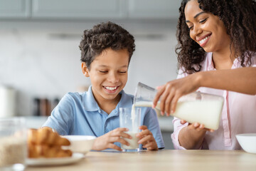 Loving african american mother pouring milk for her son