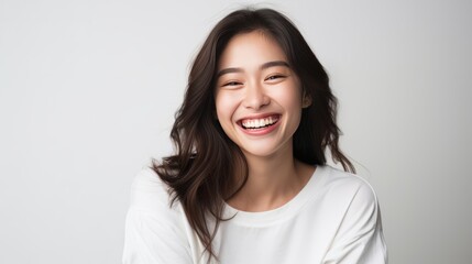 A woman with long hair and a white shirt is smiling