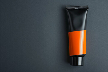 Contemporary cosmetic cream tube with a vibrant orange stripe on a slate grey isolated solid background, highlighting bold and modern design,
