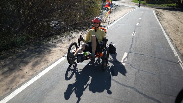 Elderly senior woman riding a recumbent electric bike on a bike path in Southern California. Filmed in.