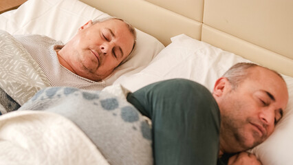 Obraz na płótnie Canvas Mature gay couple waking up in bed in the morning