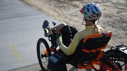 Closeup rear side view of elderly senior woman riding a recumbent electric bike on a bike path in...