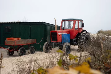 Papier Peint photo Heringsdorf, Allemagne Tractor on the beach of the Baltic Sea. Tool for beach maintenance and for pulling fishing boats ashore. tractor stands behind the dune.