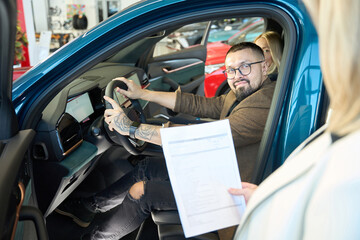 Lady car saleswoman hands a contract to a young buyer