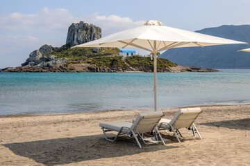Fototapeta na wymiar Sunbeds with umbrella on sandy beach of Agios Stefanos. The Greek island of Kos